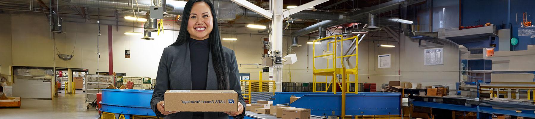 A person holding a USPS Ground Advantage package in a delivery center.